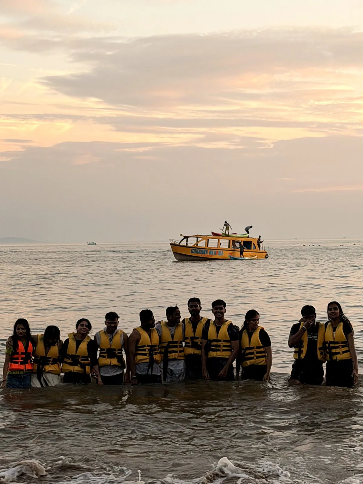 Group photo in the sea with the yellow boat at sunset