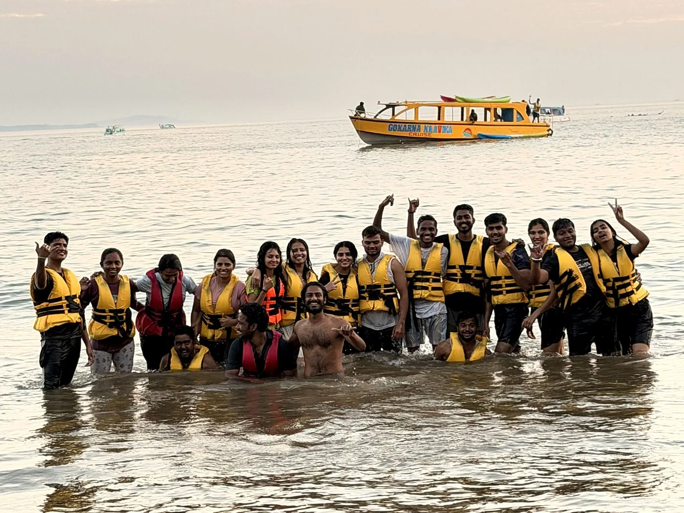 Group of guests in life jackets in the sea with the yellow Naavika boat behind